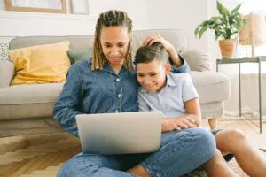 Photo by Ivan Samkov: https://www.pexels.com/photo/woman-and-young-boy-sitting-on-floor-with-laptop-4624915/ A mother and son sitting on the floor reading about early orthodontic signs online.