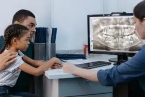 https://www.pexels.com/photo/a-man-and-a-girl-having-a-dental-consultation-with-a-dentist-6502163/ A father and daughter speak with a family dentist about her dental x-rays