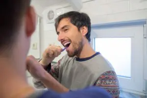 https://www.pexels.com/photo/man-in-gray-long-sleeve-shirt-brushing-teeth-6670234/ Adult male with short brown hair brushing his teeth